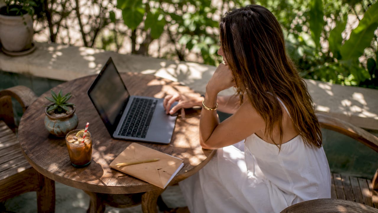 Woman researching swimwear alternatives on laptop at home balcony