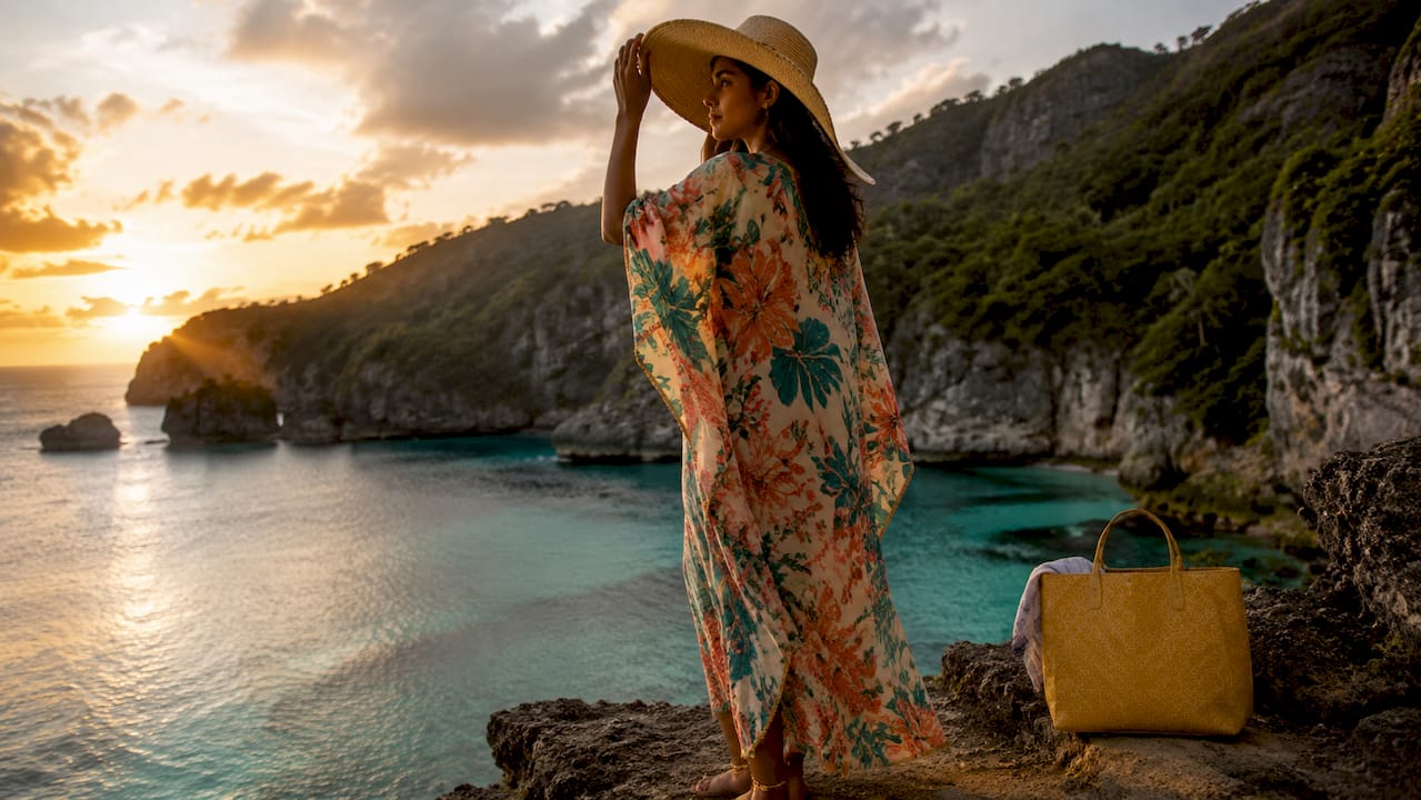 Woman wearing bold floral caftan on tropical beach