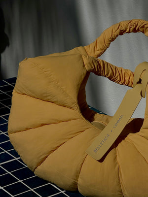 Le Sac handbag - L'ANIMAL Yellow puffer bag with visible on a dark tiled floor.